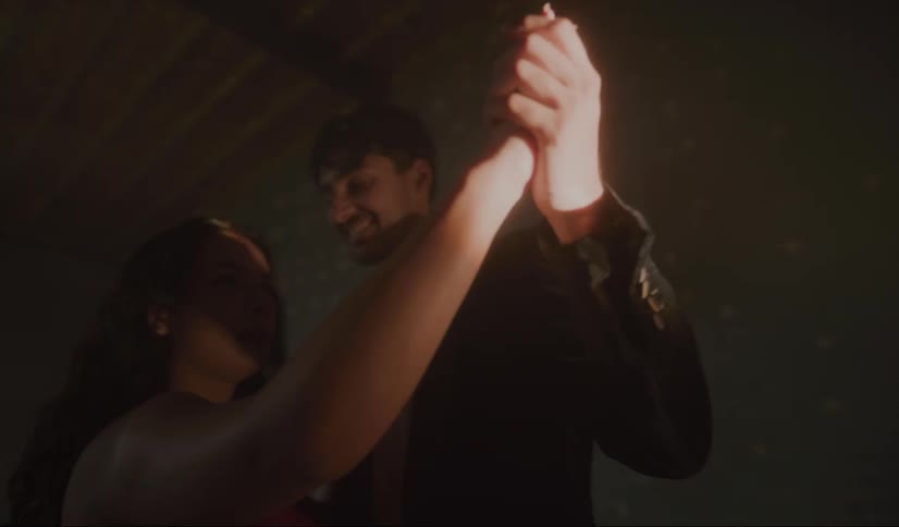 A young man smiles at the shimmering lights while slow dancing with his date