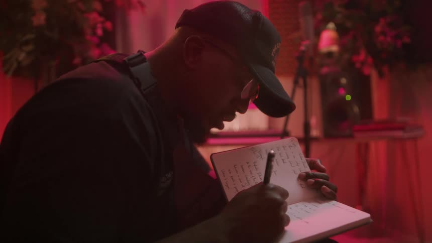 A musician sings as he writes lyrics in a notebook