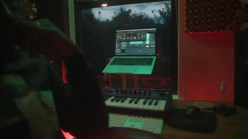 A musician looks at a laptop with a recording on it