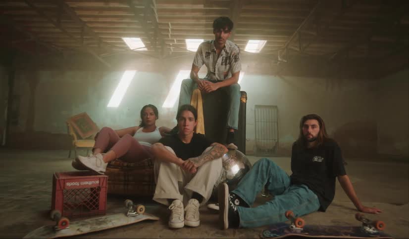 Group of friends sitting on the floor of an abandoned warehouse looking at the camera