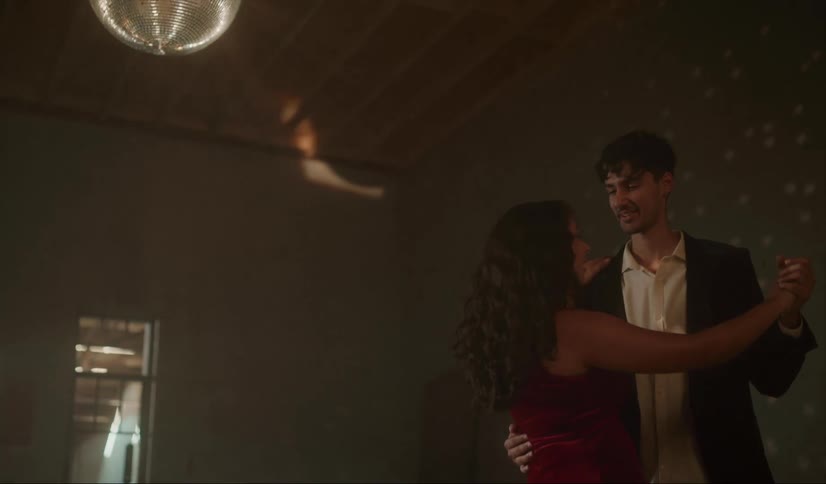 Young happy couple dancing inside an abandoned warehouse under a mirror ball