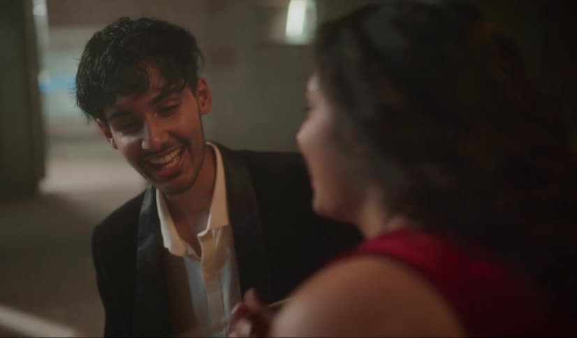 A woman uses a brush to paint on a small canvas as her date begs to see it
