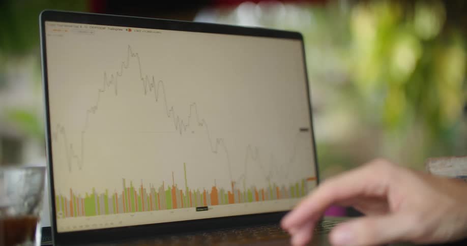 Man side scrolls chart on laptop screen with greenery in the background
