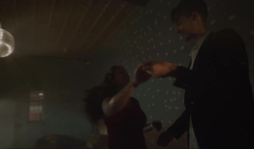 Couple dances in room with mirror ball scattering reflected light