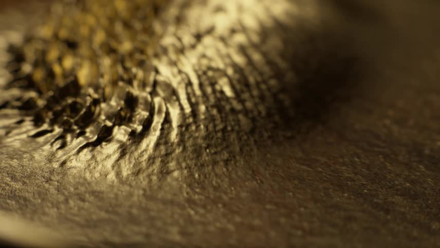 Golden grains shift and form peaks and ridges with vibration