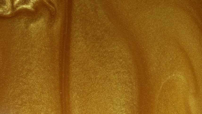 Golden metallic mixture swirls and glints as it flows