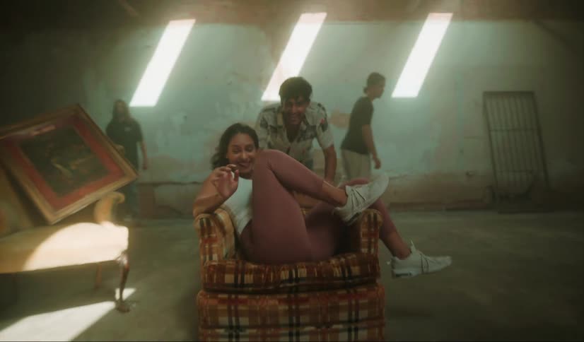 A woman runs to sit in a chair and her boyfriend pushes and twirls her around
