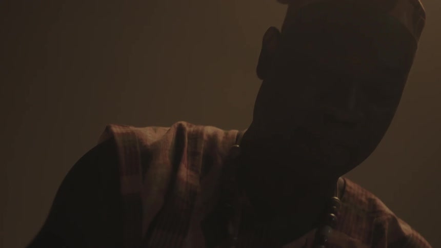 A man is swinging his hands down drumming in a dark area