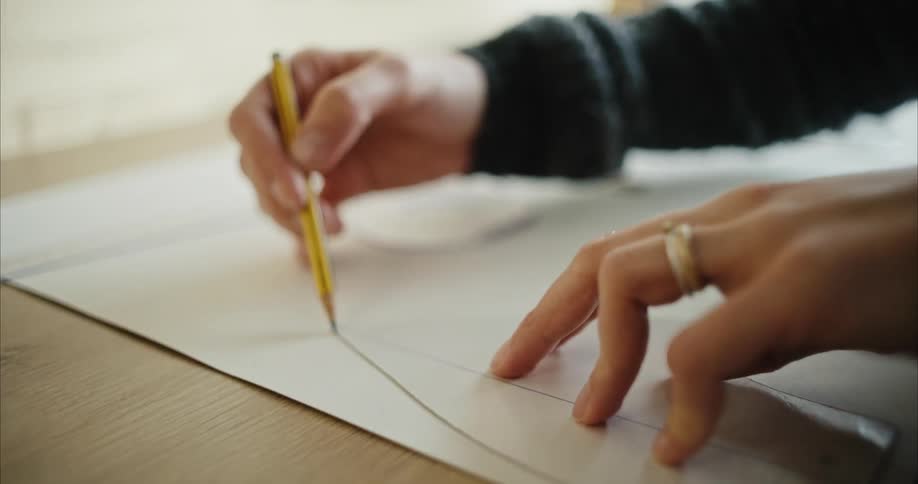 A woman uses a pencil to trace a line from a pattern form onto large paper