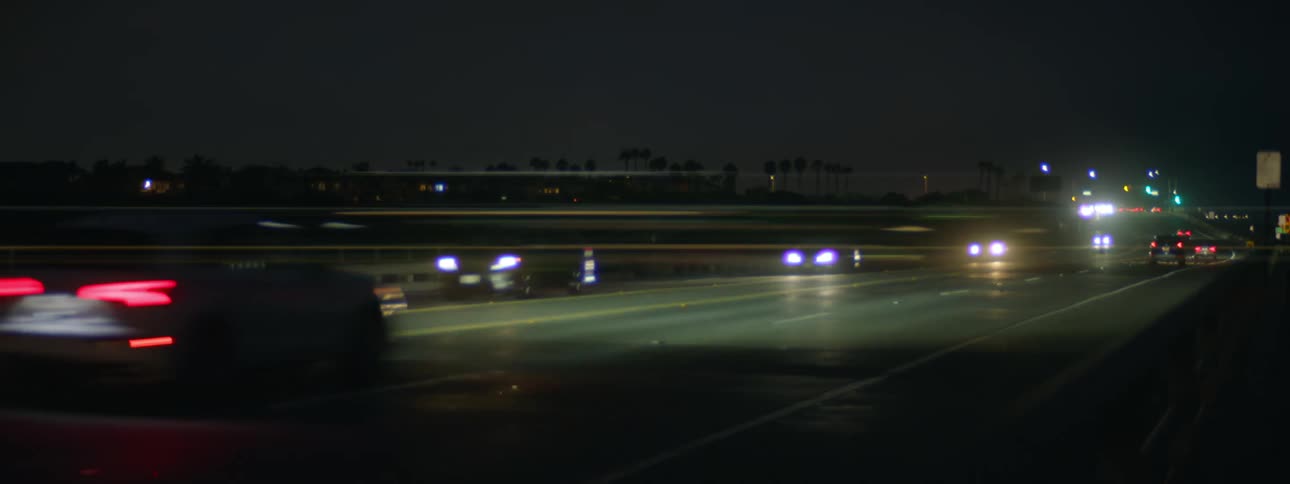 Vehicles drive down a damp highway at night