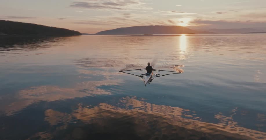 A man paddles his kayak backward in a lake