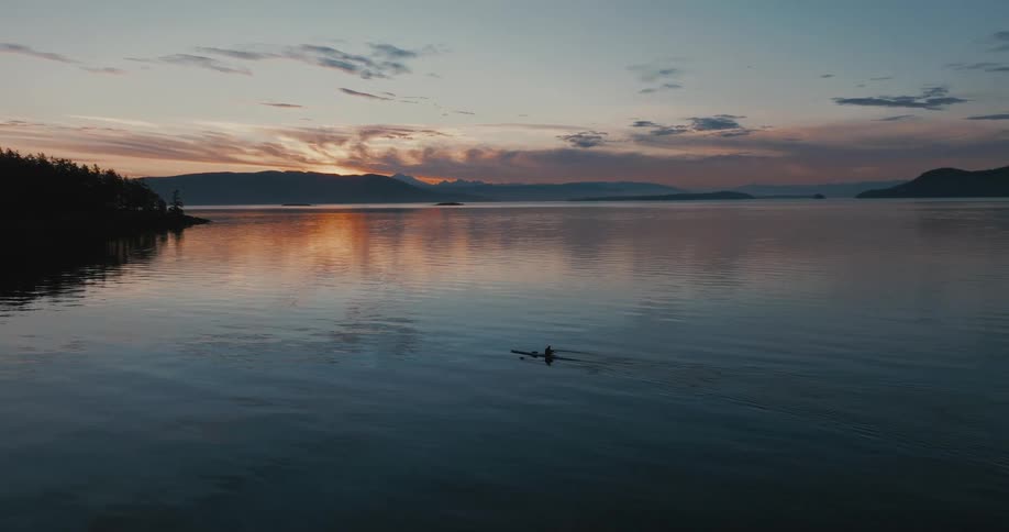 A person is rowing at sunrise