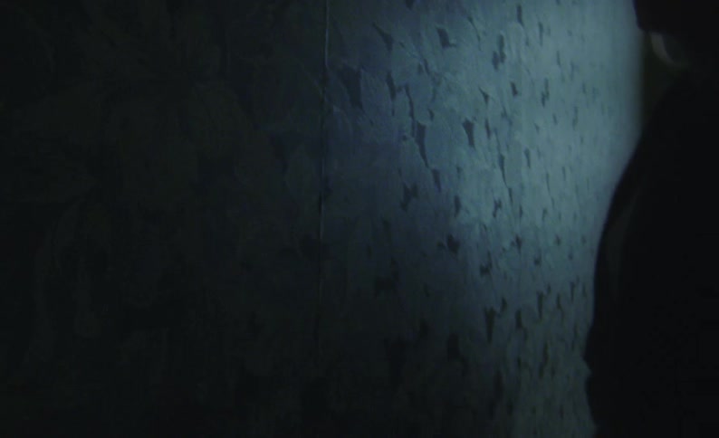 Woman touching wall with wallpaper and leaning is silhouetted against the window light