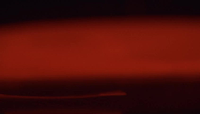 Photograph sinks in liquid filled container until it hits the bottom in a dark room