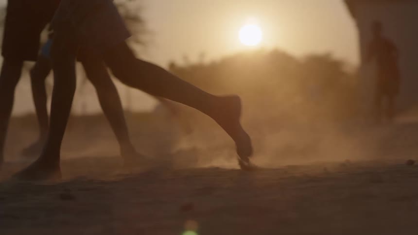 Children are playing soccer at sunset