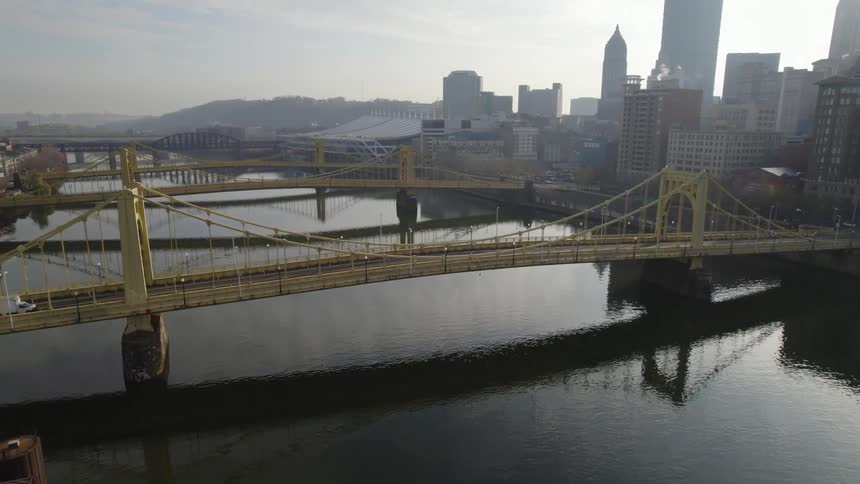 Aerial view of a white truck crossing one of many bridges over a river next to the city skyline at morning