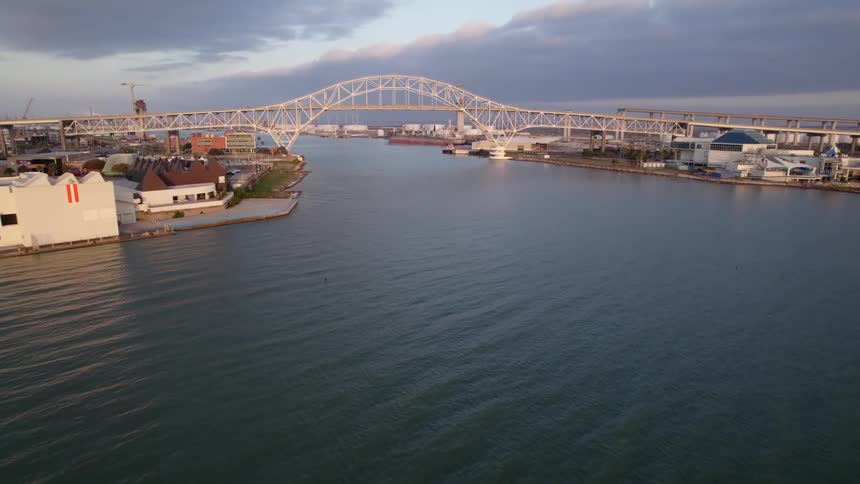 A large bridge spans a waterway in a city in the evening