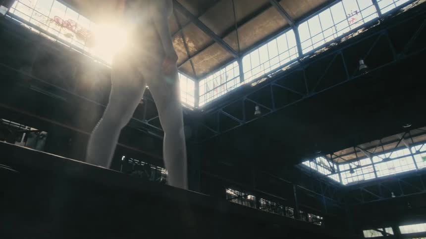 There is a young white woman that is walking indoors in the day time