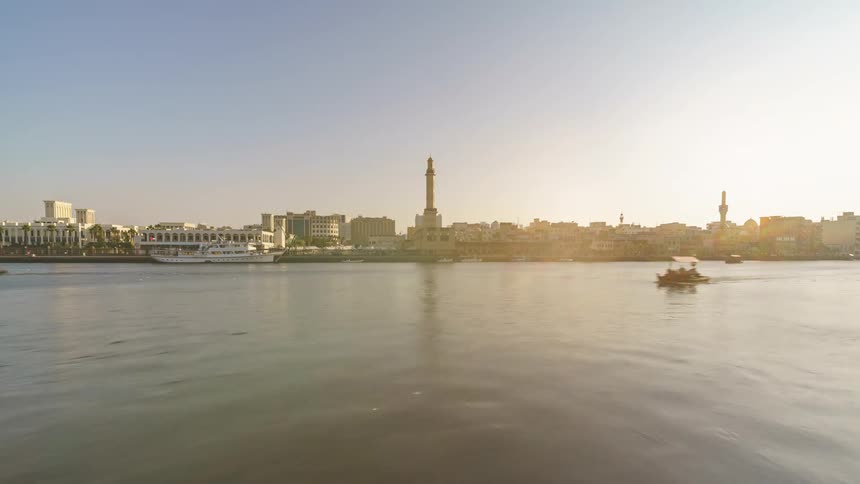 Time lapse of boats sailing in the water with a city skyline in the distance