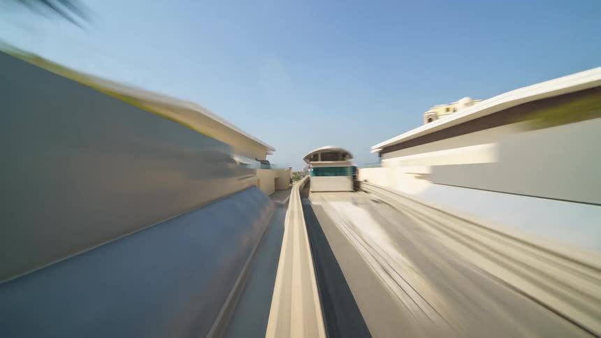 Public transit tracks lead across seaside city paralleling highway in place