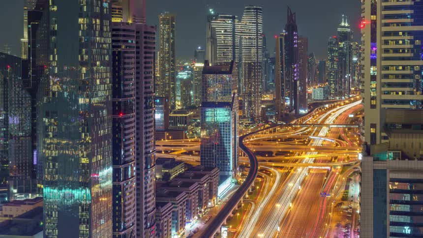 Cars are driving downtown on the high way at night time