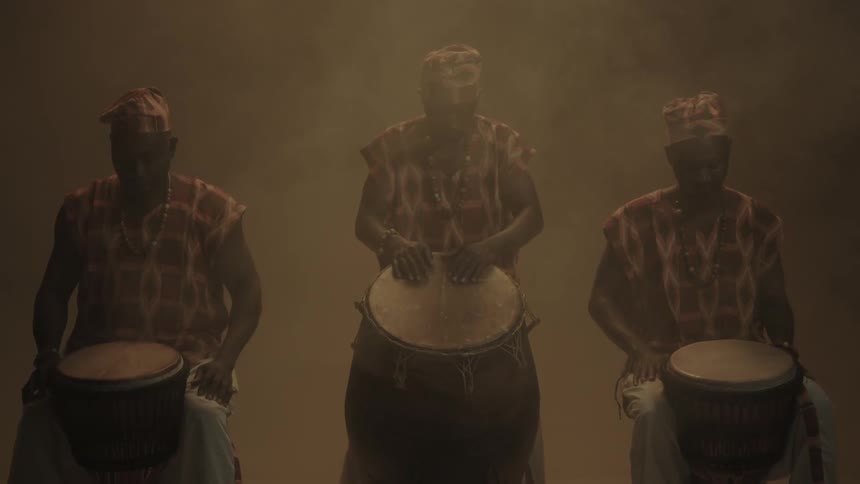 Three men sitting by bongos in a hazy room