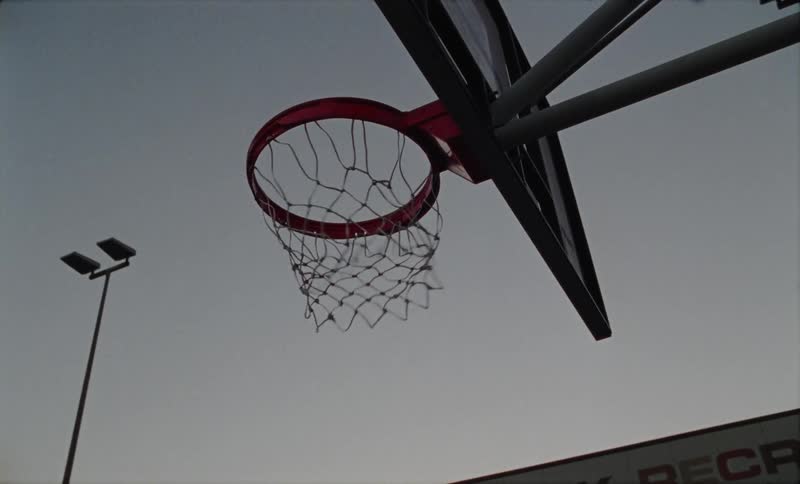 The view is of a basketball hoop outside in the day time