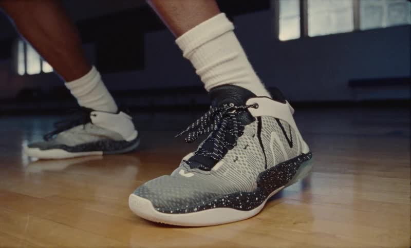 Basketball player wearing white socks and a pair of gray sneakers plays basketball in basketball court
