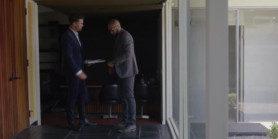 Real estate agent in suit shows the rooms to bald man wearing blazer jacket dark pants and shoes in building