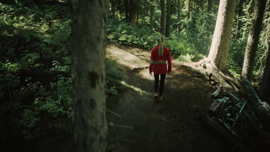 A woman walks through a forest