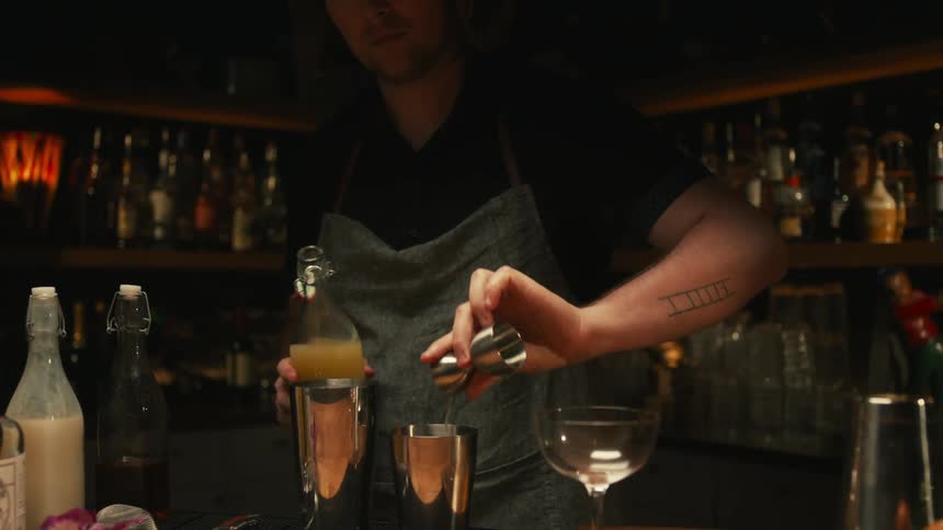 A bartender is preparing some drinks at the bar for some people