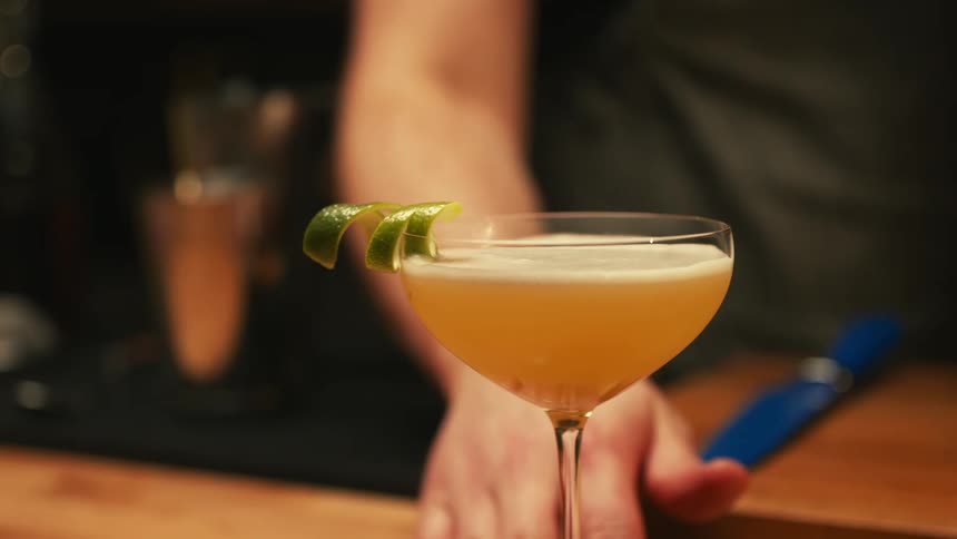 A bartender serves a mixed drink