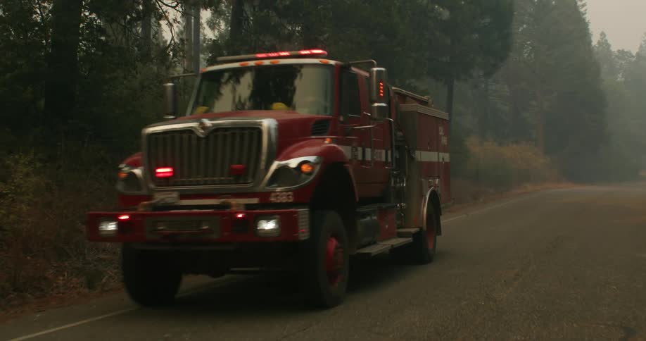A fire engine drives past a smoky forest