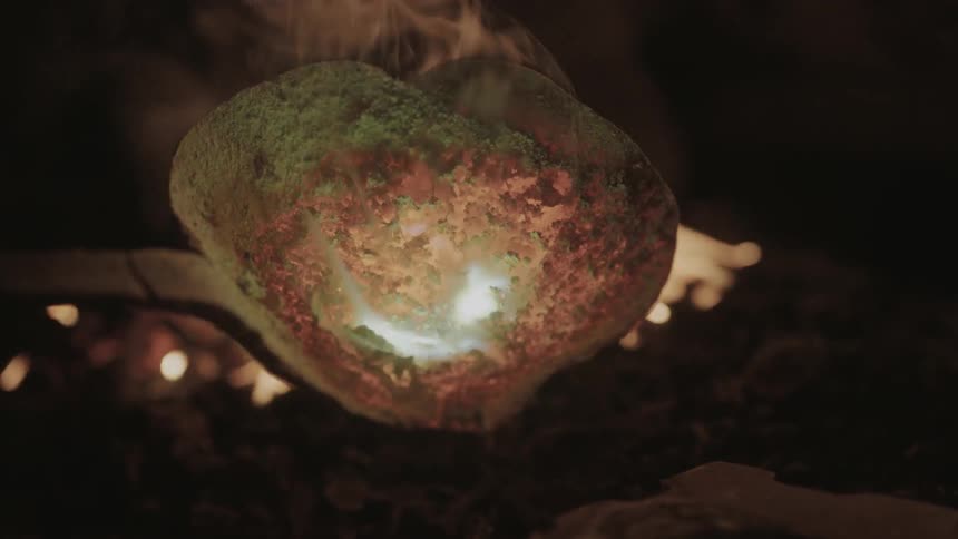 A large spoon is being held over a fire