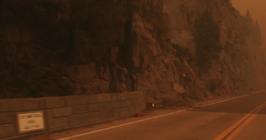 The fire truck drives on the road past the burning forest