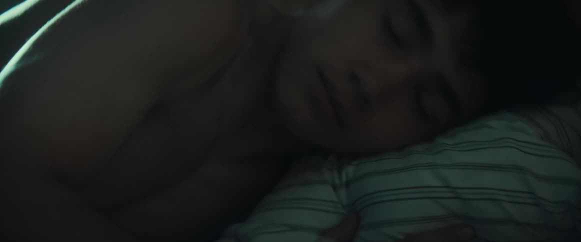 Shirtless young man trying to sleep on his bedroom at night tossing and turning on the bed