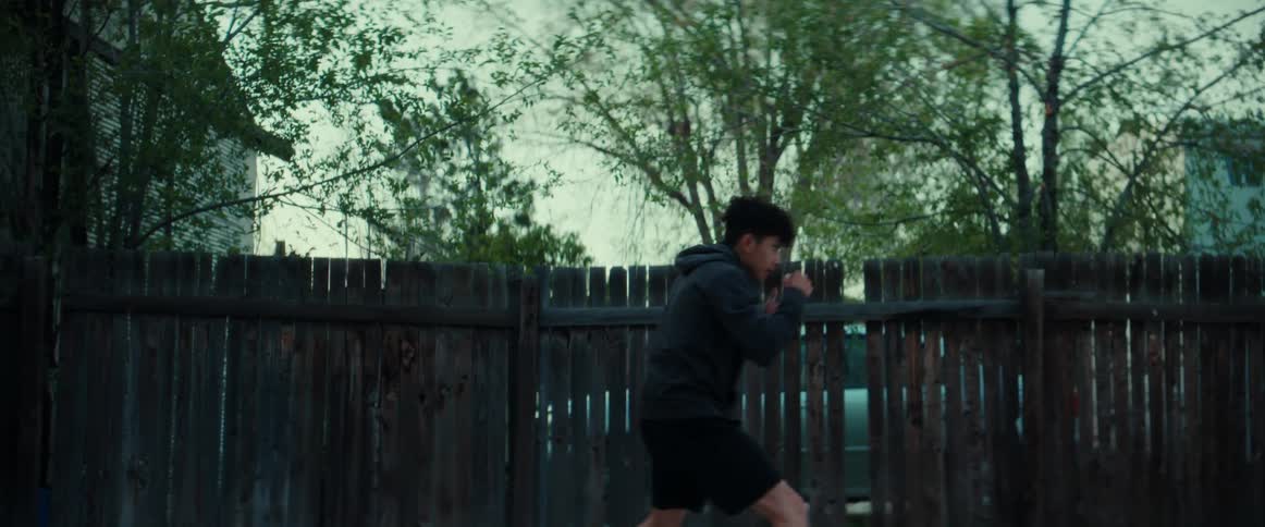 A young man shadow boxes outdoors in the evening
