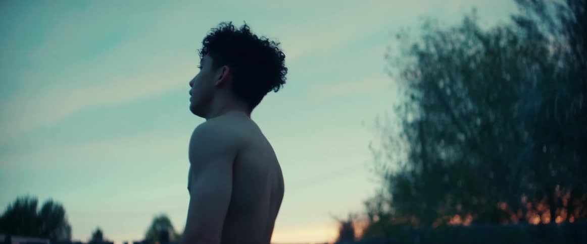 Young muscular shirtless teenager catching his breath on the backyard at evening