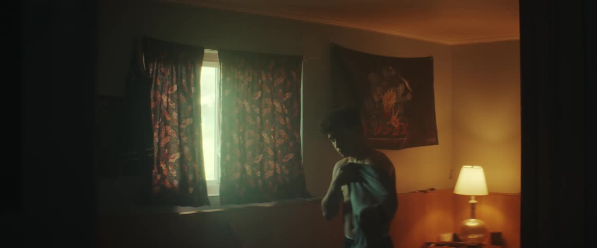 Young shirtless man dress with a shirt in the bedroom at morning