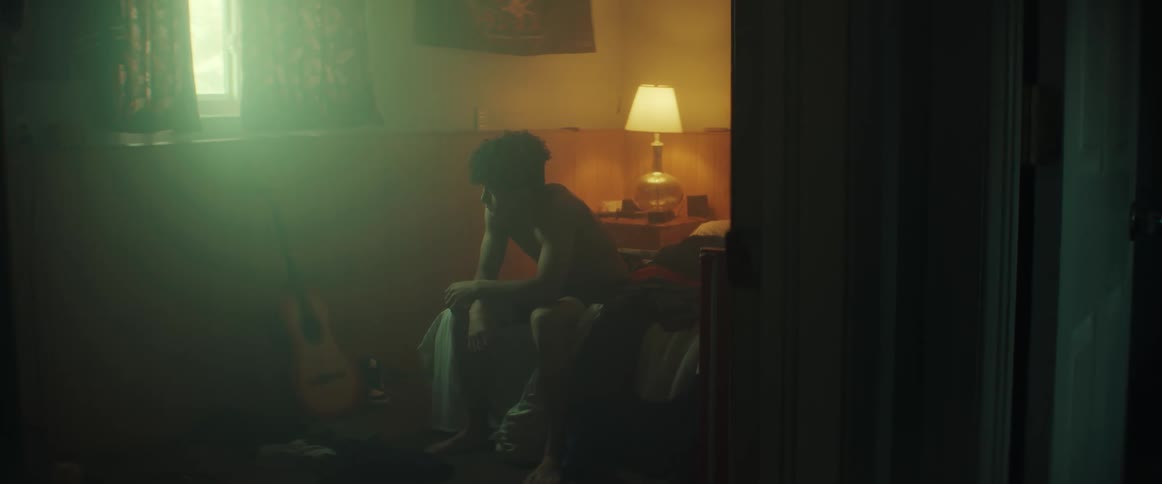 A man sitting on a bed looking frustrated