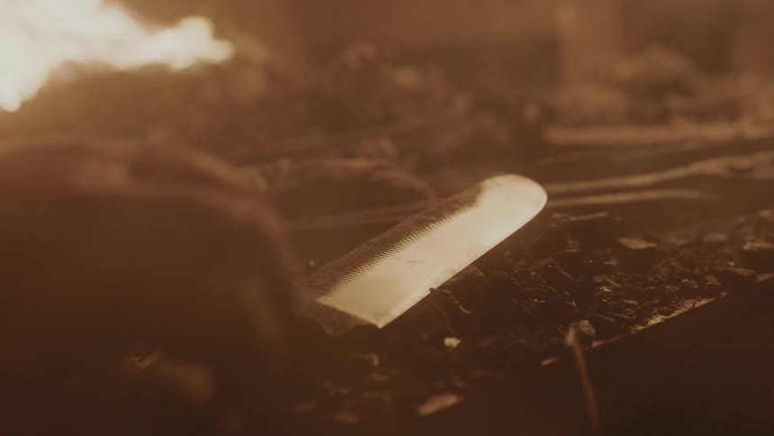 A person puts a knife down by a fire