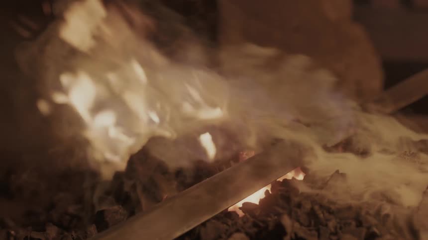 Someone heats a sword over a fire