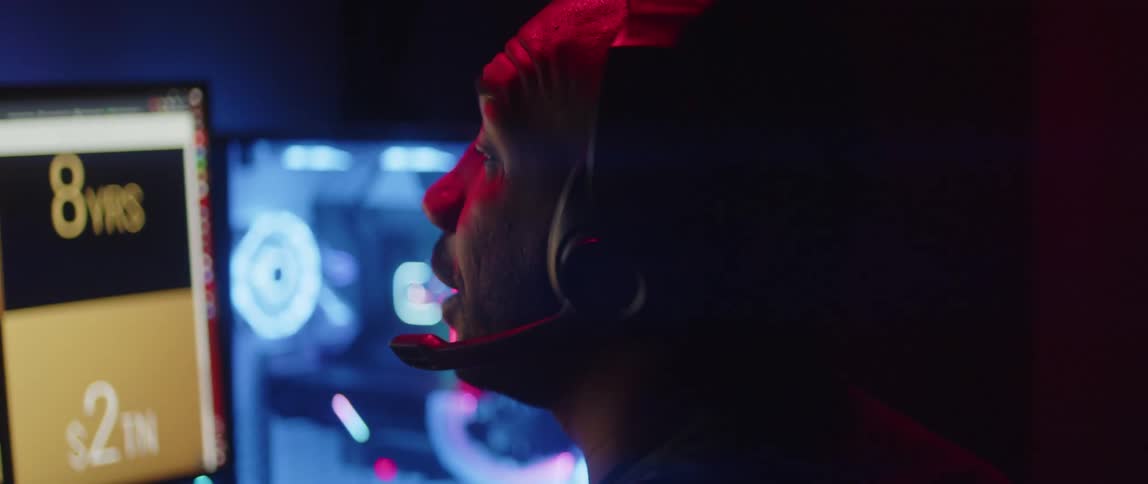 A man talks to someone on a headset while working on his computer