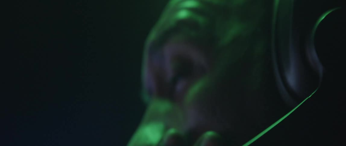 A man stretches his neck while wearing over ear headphones with a microphone