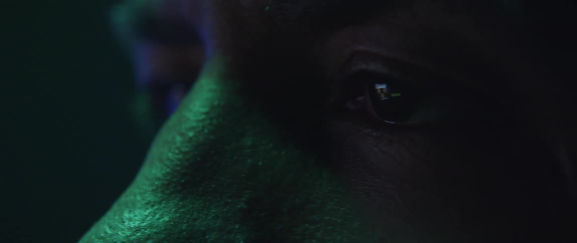 Close up of the eyes of a man looking at a screen under changing colorful rgb lights