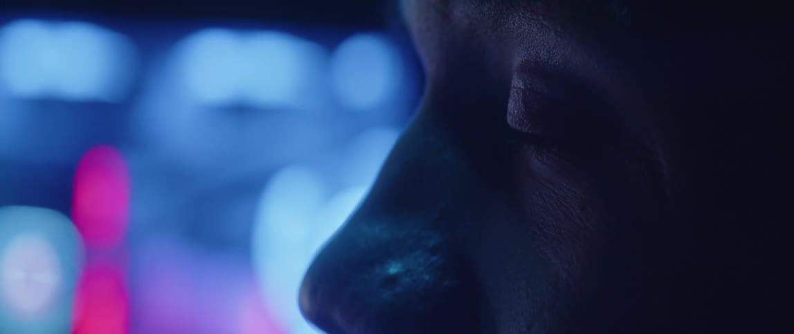 Man widens his eyes in surprise as colored lights shine on him and nearby monitor