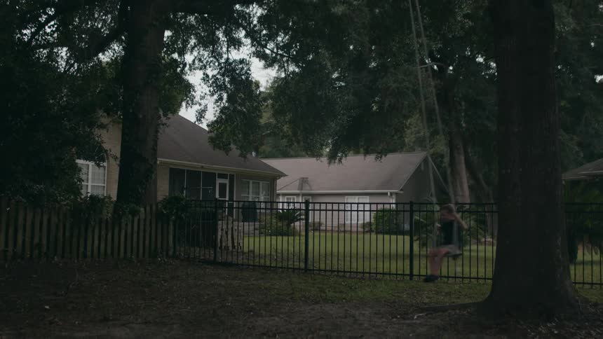 Boy swings on swing tied to large tree in yard