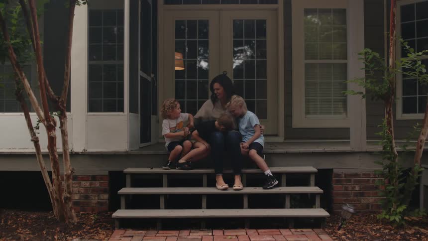 A group of children join their mother on the steps in front of a house to pose for the camera