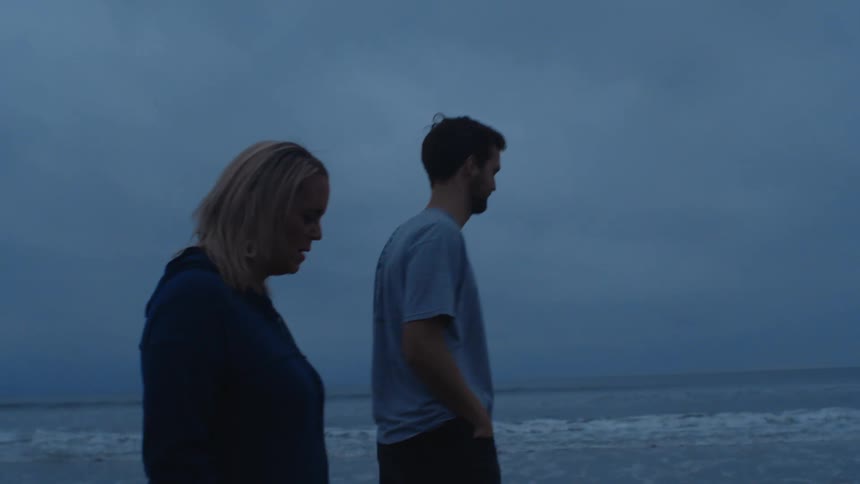 Young relaxed couple walking on a beach near the ocean at evening