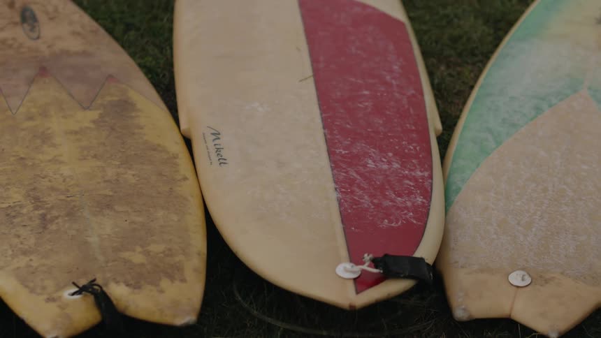 Child walks back and forth on surfboards lying on grass